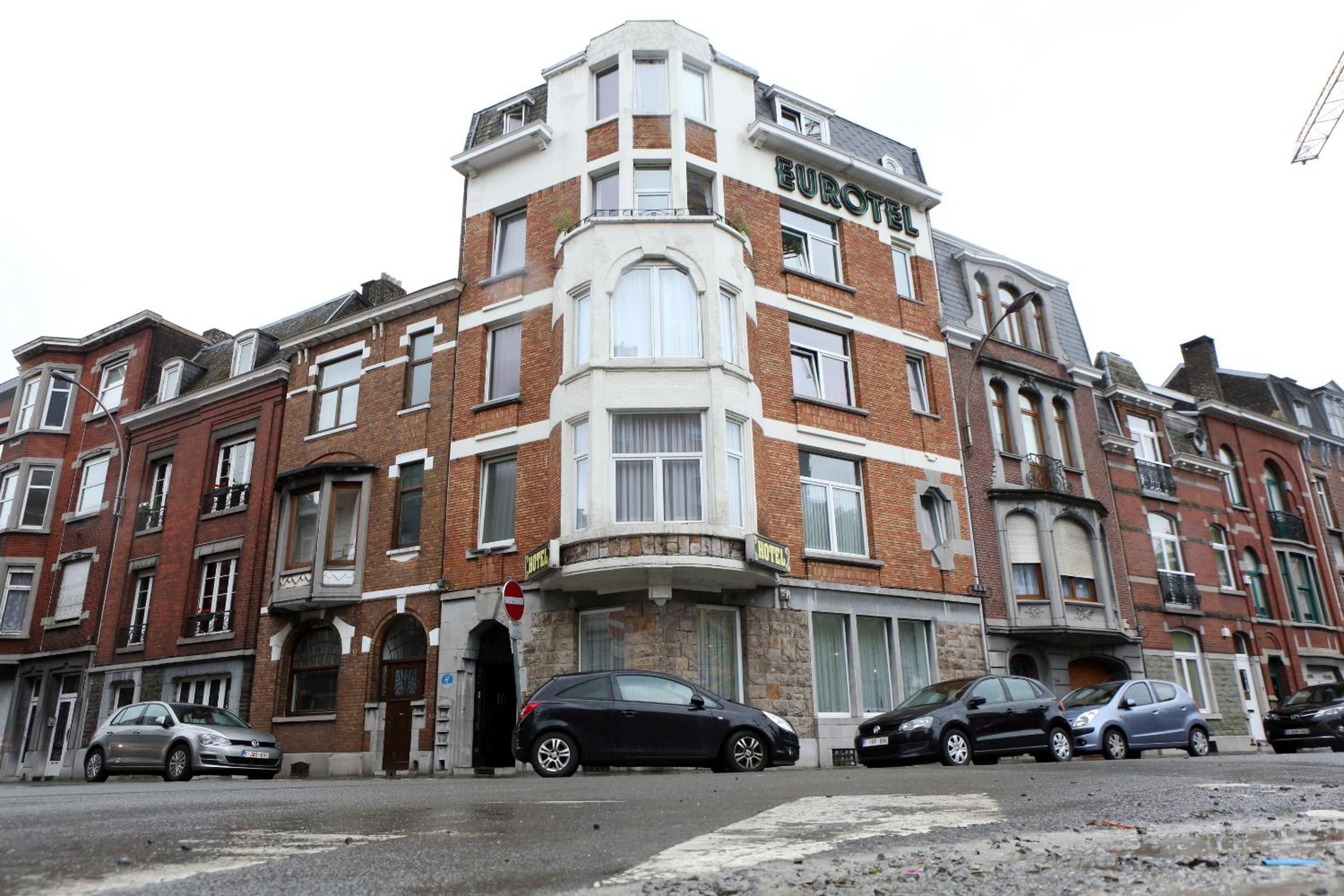 Un bâtiment d’angle avec une enseigne « EUROTE » et, en dessous, une enseigne « HÔTEL ». Des voitures sont garées devant.