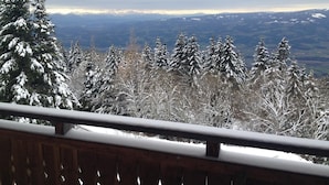 Eine verschneite Landschaft mit einem hölzernen Geländer im Vordergrund.