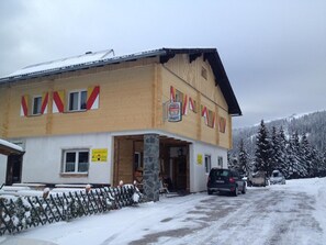 En byggnad med ett sluttande tak, en skylt och en snötäckt mark.