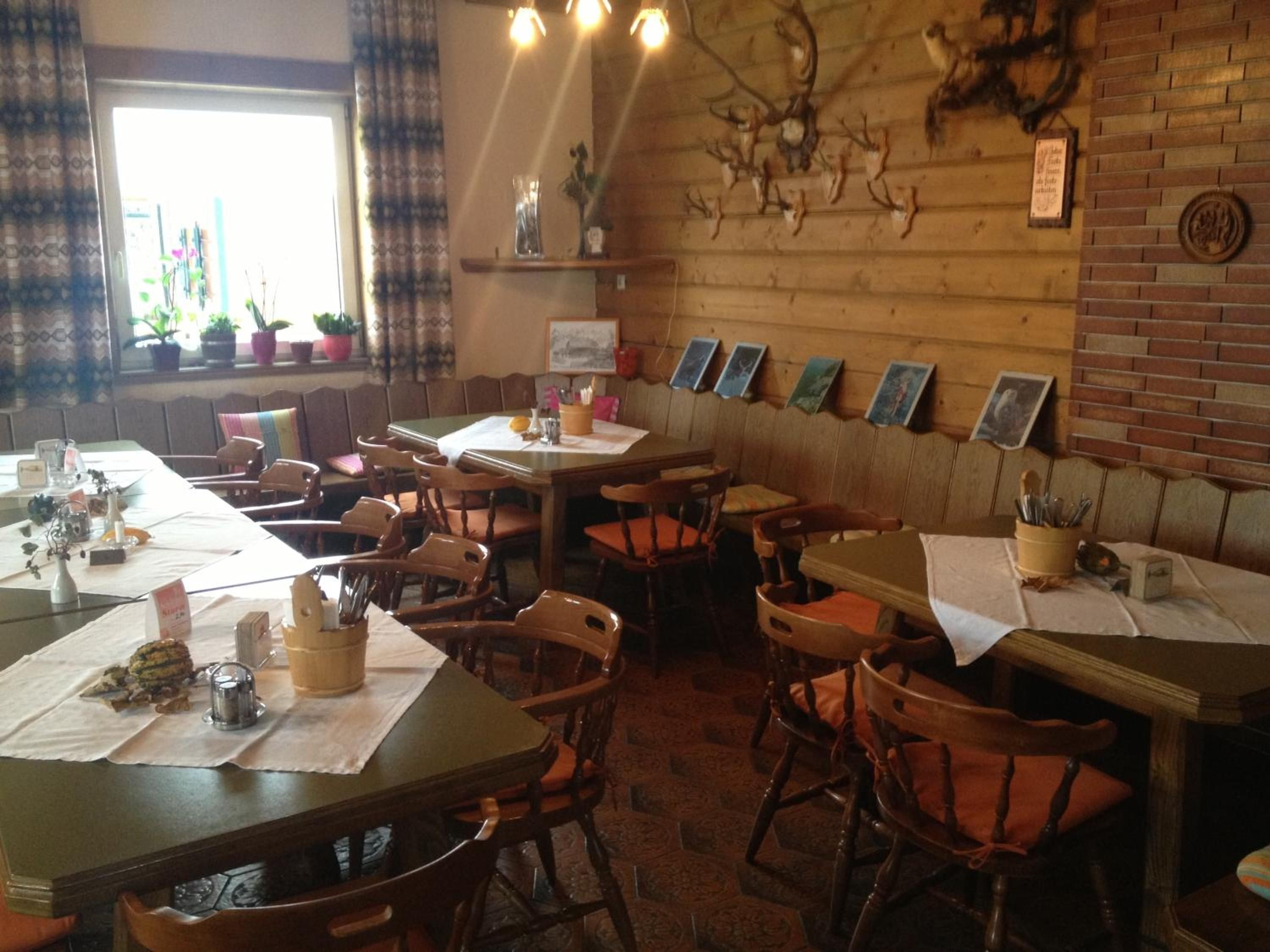A restaurant interior with wooden walls, multiple tables, and chairs.