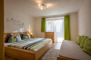 Un dormitorio con una cama de madera, una mesita de noche, una cortina verde y una ventana.