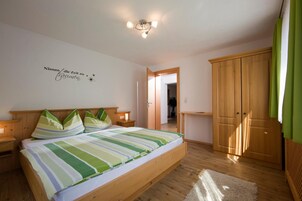 Un dormitorio con cama, mesitas de noche, un armario y una pared con un letrero decorativo.