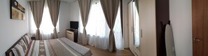 A bedroom with a bed, a dresser, a television, and curtains. - Boulevard Sea Residence (Nessebar)
