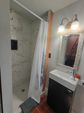 Une salle de bain avec une douche, un lavabo et un miroir avec éclairage.