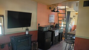 Cozinha compacta com televisão de tela plana, micro-ondas e geladeira.