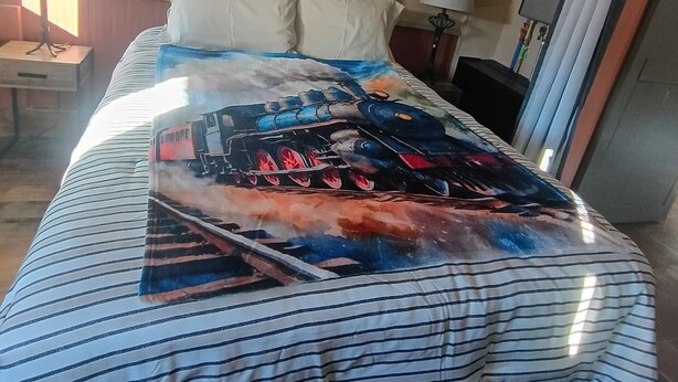 Quarto de hotel com cama, janela, escrivaninha e luminária.