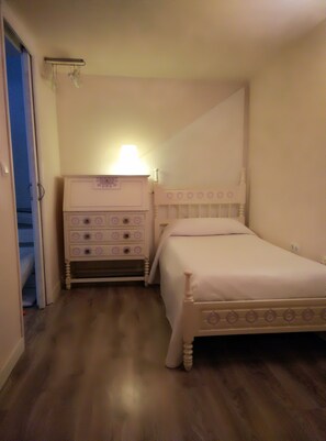 Une chambre à coucher avec un lit, une commode à tiroirs et une table de chevet avec une lampe.