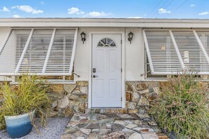 A house with a stone foundation, a white door, and shutters on the windows. - Pond-view 3BR with fenced yard near Gulf beaches (Englewood)