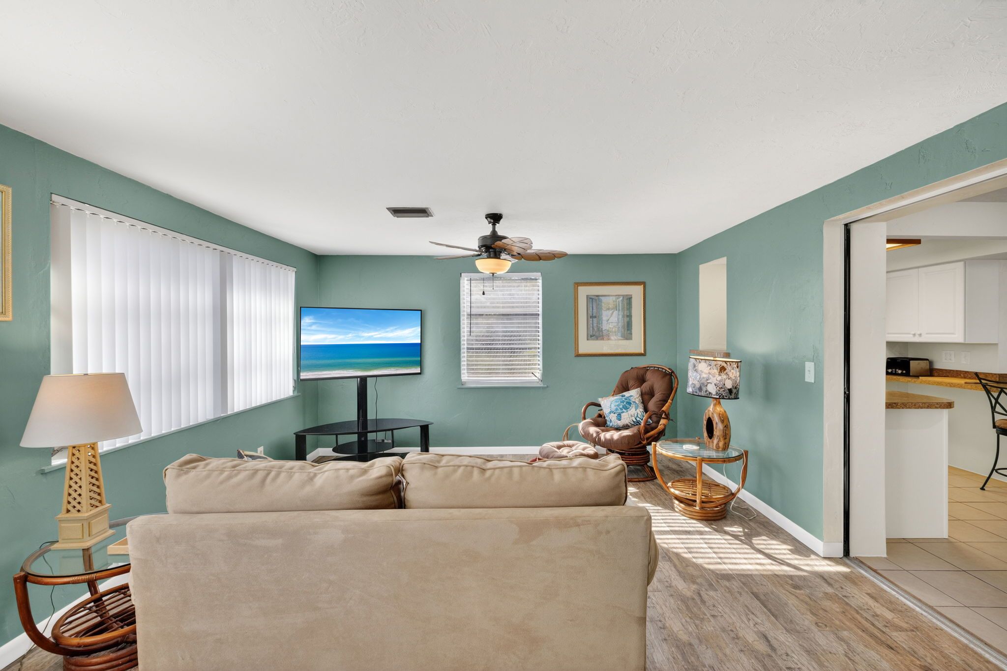 A living room with a sofa, a television, a ceiling fan, and a dining area with a table and chairs.