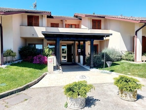 A two-story building with a covered entrance, a garden with shrubs and a pathway leading to the entrance. - Montebello Park Hotel (Perugia)