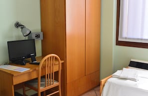 Een kamer met een houten bureau, een computer, een stoel, een bed en een raam met gordijnen.