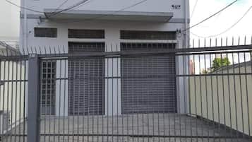 Edifício de dois andares com portão fechado, garagem e placa visível.