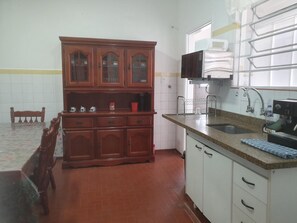 Cozinha com armários de madeira, micro-ondas, pia e uma cadeira.