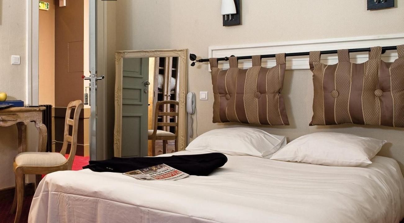 Une chambre d’hôtel comprenant un lit, une chaise, un bureau, un miroir et une armoire.