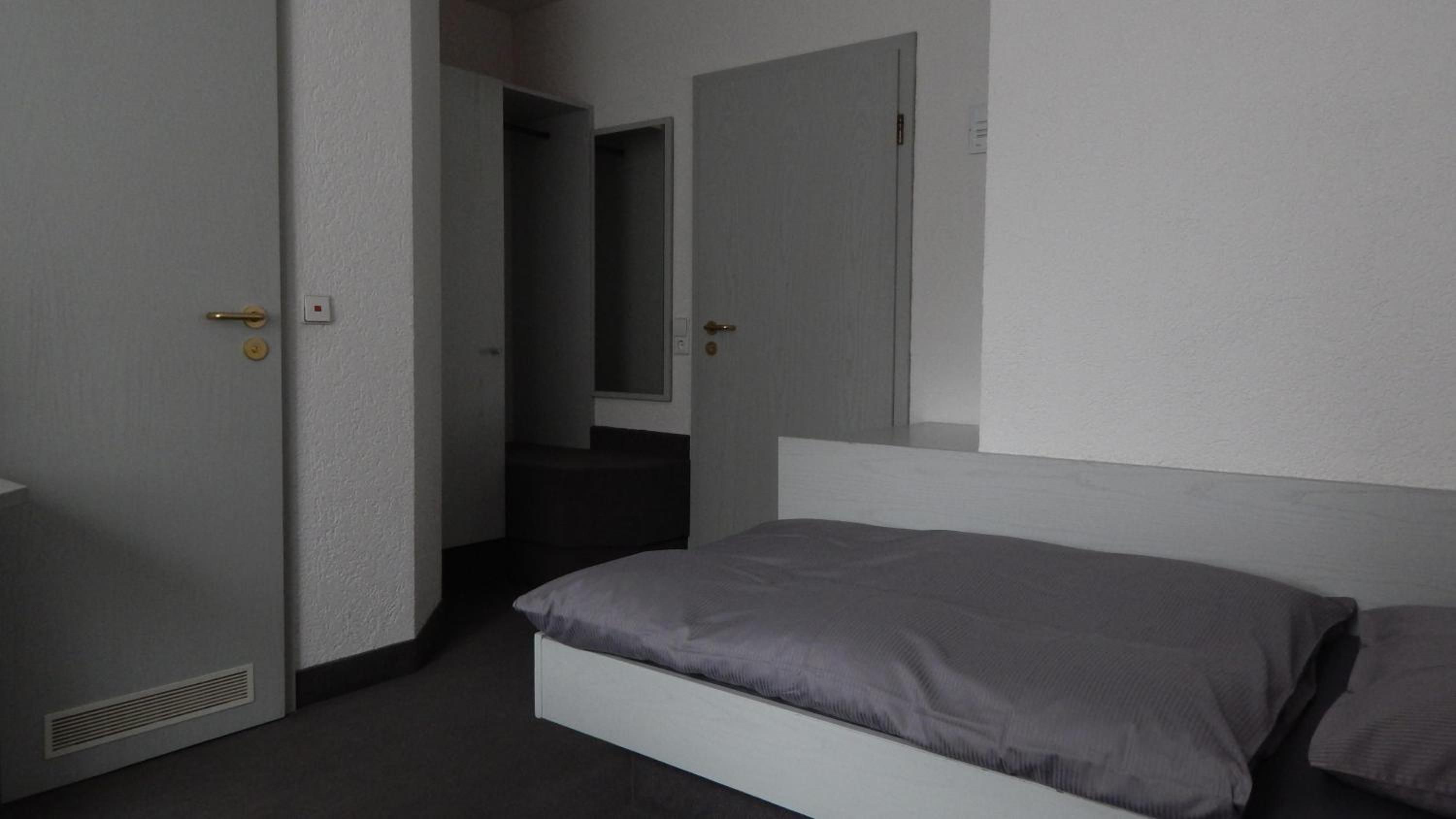 Una habitación de hotel con cama, puerta y espejo.