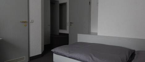 Una habitación de hotel con cama, puerta y espejo.
