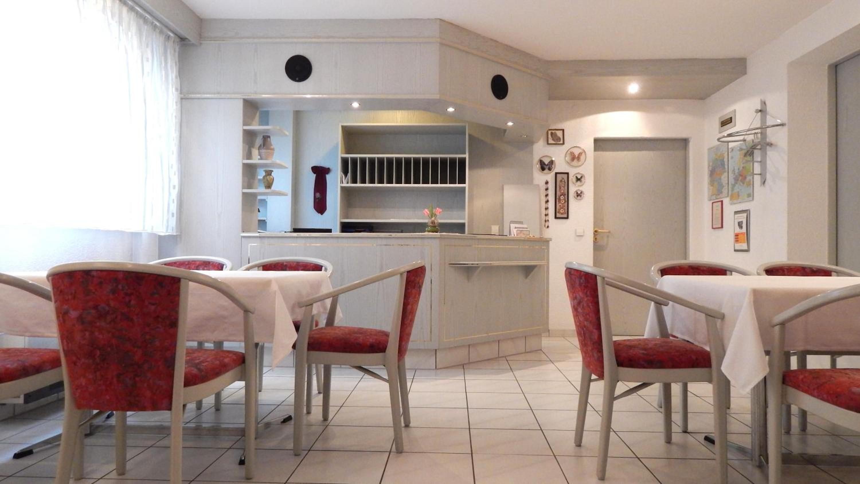 A dining area with a bar, red upholstered chairs, and a tiled floor.