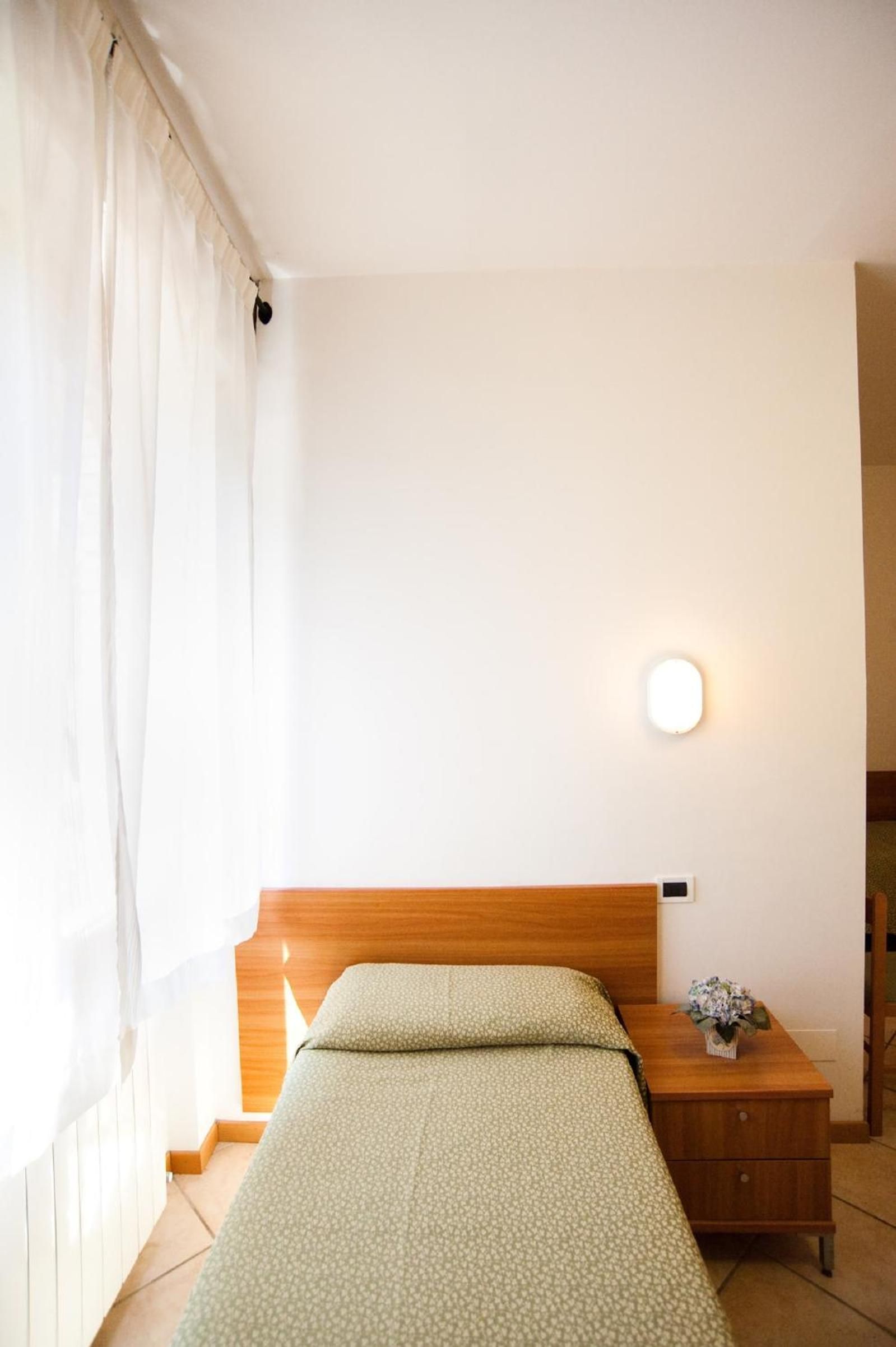 A single bed with a wooden headboard in a room with white walls and a small bedside table.