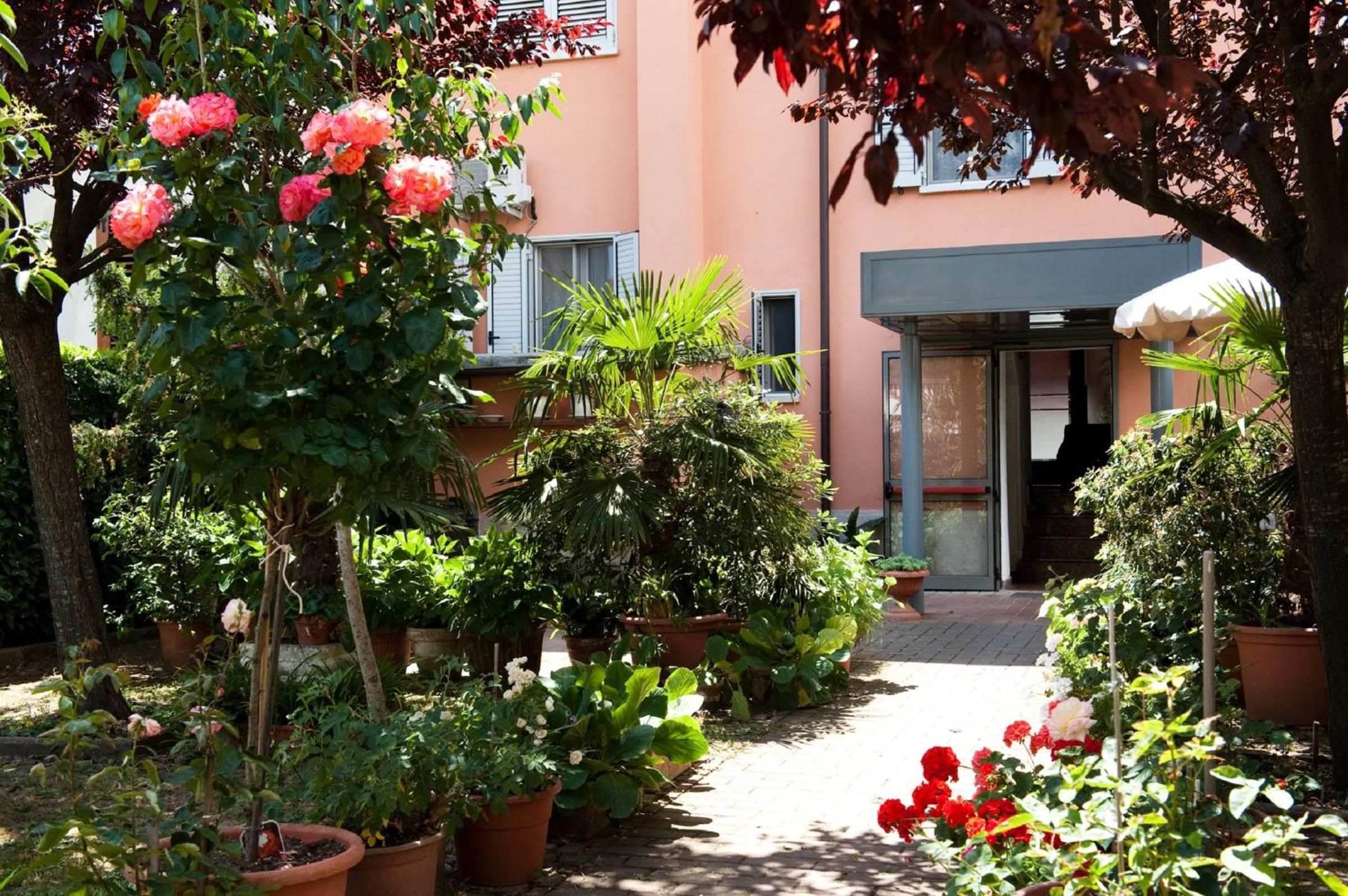 Um jardim com vasos de plantas e flores que leva a uma entrada de edifício.