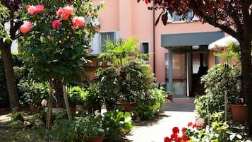 Um jardim com vasos de plantas e flores que leva a uma entrada de edifício.