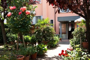 Um jardim com vasos de plantas e flores que leva a uma entrada de edifício.