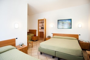 Quarto de hotel com uma cama grande, uma cama menor, escrivaninha, cadeira, mesa de cabeceira, guarda-roupa e um quadro na parede.