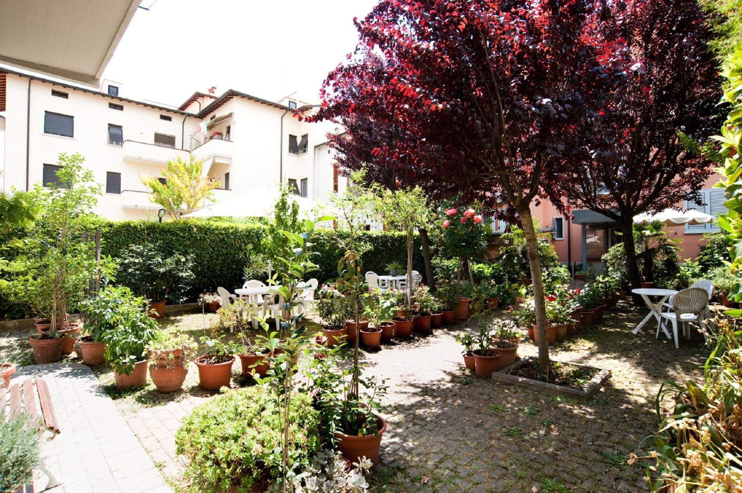 Ein Innenhof mit Topfpflanzen, Gartenmöbeln und einem Gebäude im Hintergrund.
