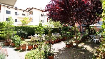 Un cortile con piante in vaso, mobili da esterno e un edificio sullo sfondo.