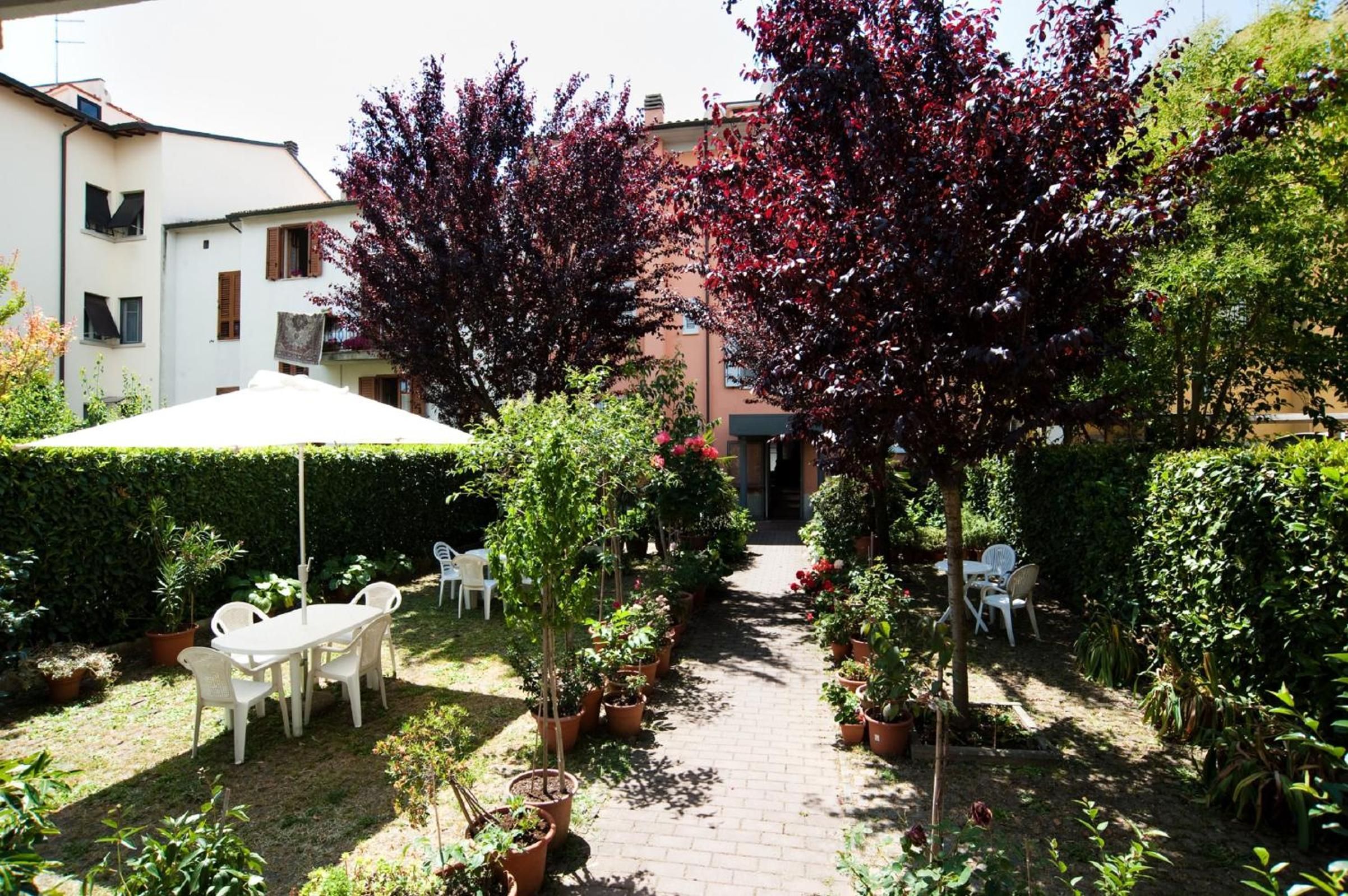 A courtyard with a paved pathway, potted plants, and outdoor furniture.