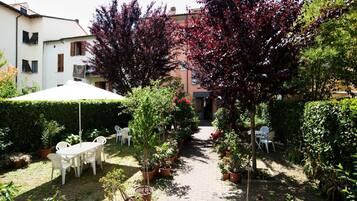 Un cortile con un percorso pavimentato, piante in vaso e mobili da esterno.
