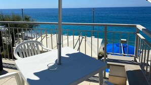 Ein Balkon mit Tisch, Stühlen und Blick aufs Meer.