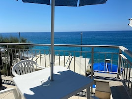 Un balcón con mesa, sillas y vista al mar.