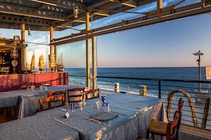Un área de comedor al aire libre con mesas dispuestas para dos, con vista al mar.