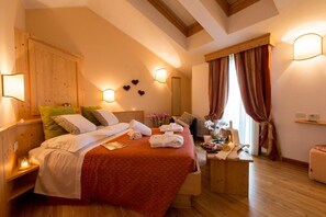 Habitación de hotel con cama, mesita de noche, lámpara, cortinas y cabecero de madera.