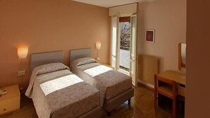 Ein Hotelzimmer mit zwei Betten, einem Schreibtisch und einem Stuhl.