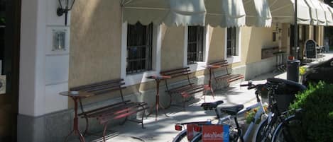 A building with outdoor seating, a bicycle, and a sign.