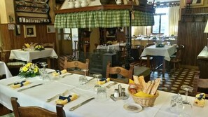 A dining area with tables set for service, a green checkered awning, and a patterned floor.