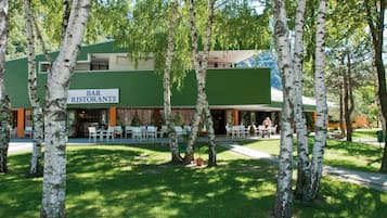 Un bar e ristorante con posti a sedere all'aperto, immerso tra betulle.
