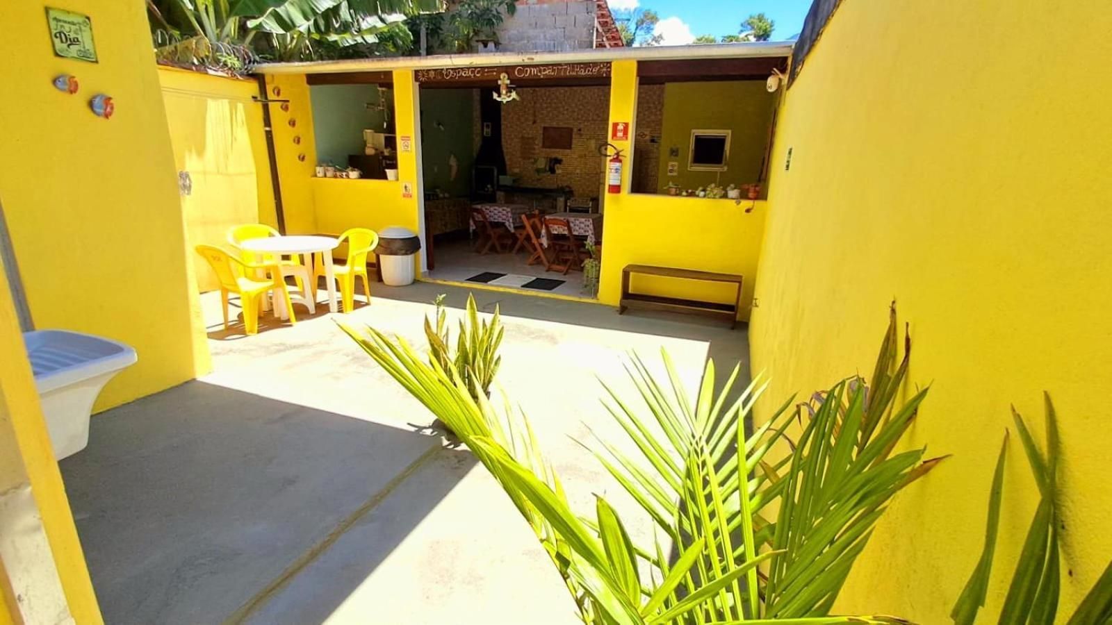 An outdoor patio area with yellow walls, a table, chairs, and a bench.