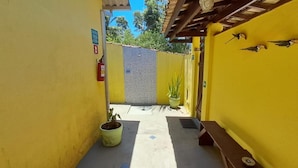 A narrow corridor with yellow walls, a fire extinguisher, a potted plant, and a bench. - Suítes Cantinho Do Sossego Em Ubatuba (Ubatuba)