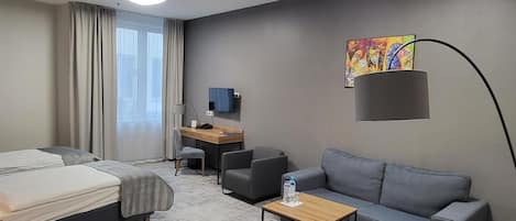 Une chambre d’hôtel moderne équipée d’un lit, d’un canapé, d’un bureau et d’une télévision.