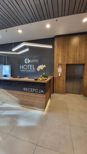 A hotel reception desk with a modern design, a digital display, and a wooden panel wall.