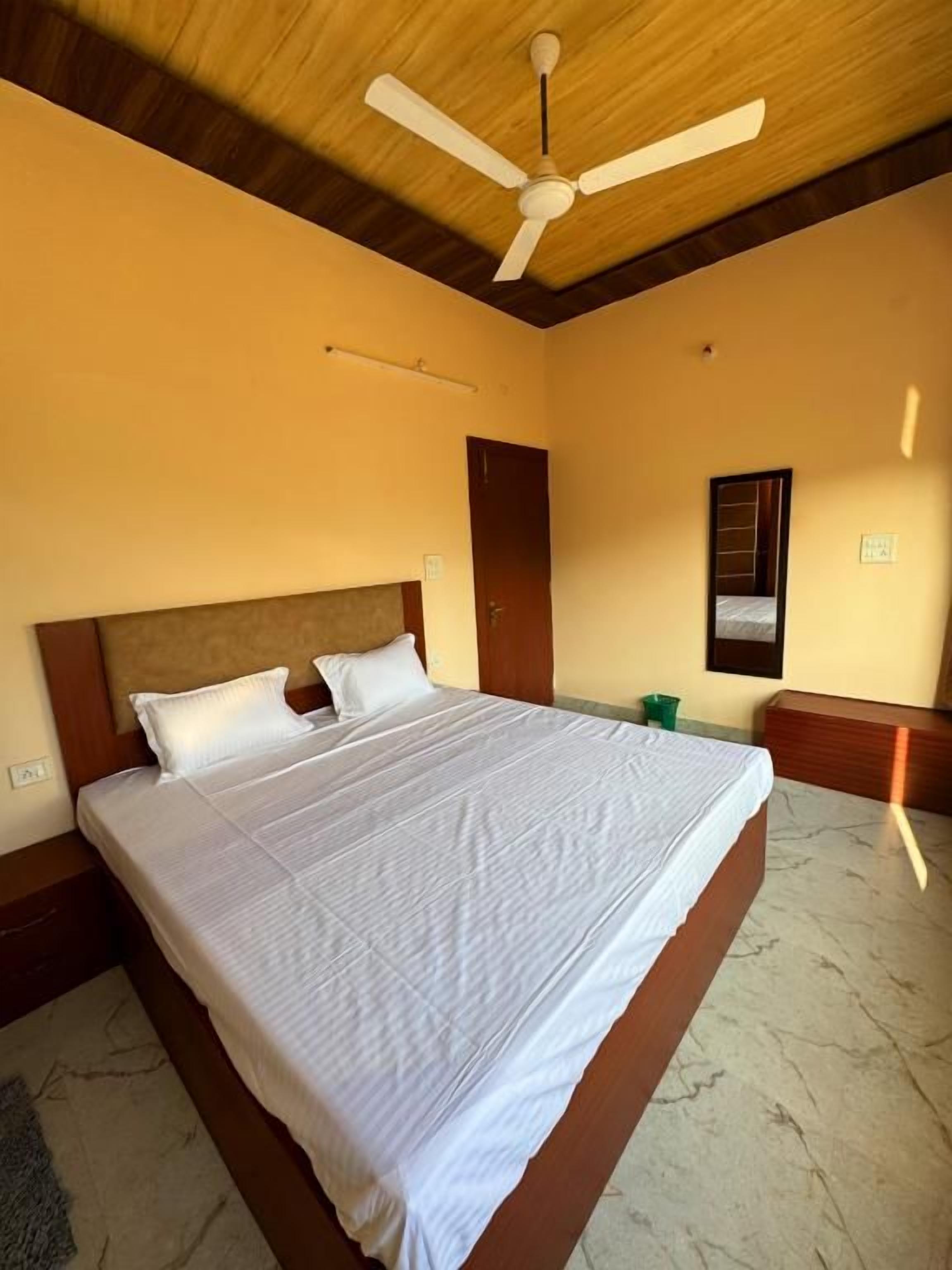 Ein Schlafzimmer mit einem Bett, Holzboden und Deckenventilator.