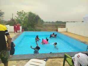 Une piscine où des personnes se baignent et profitent de l’eau, le tout dans un cadre extérieur simple et agréable.
