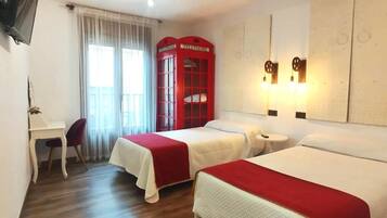 A hotel room with two beds, a desk, a chair, a TV, and a red telephone booth.