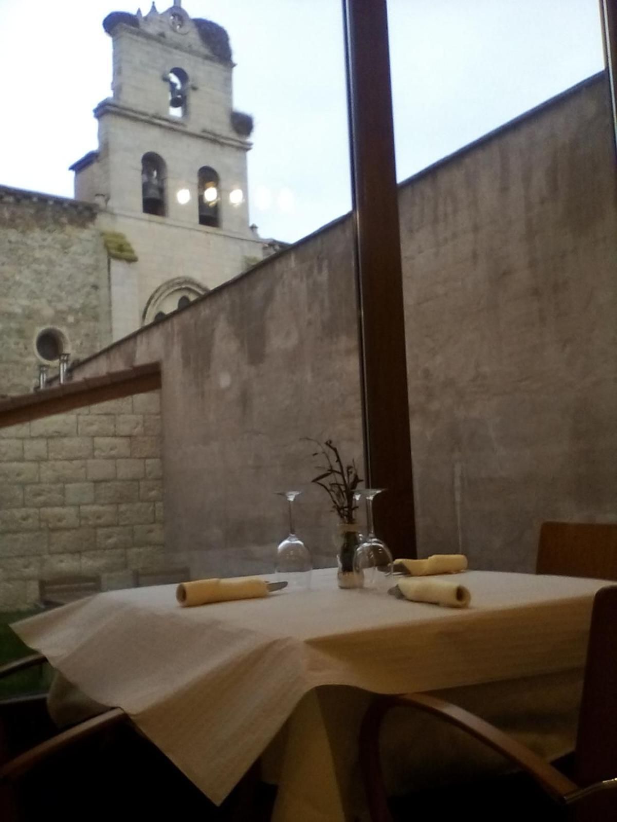 Una mesa preparada para comer, con vistas a un edificio histórico con una torre de campanas.