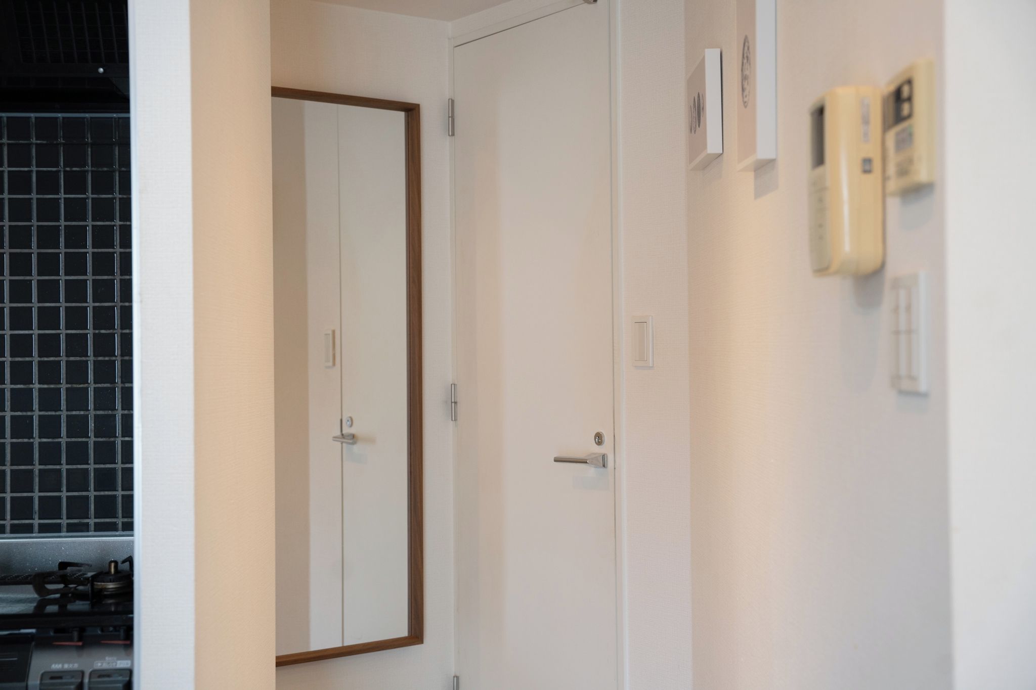 A room with two white doors, a tiled backsplash, and a wall-mounted thermostat.