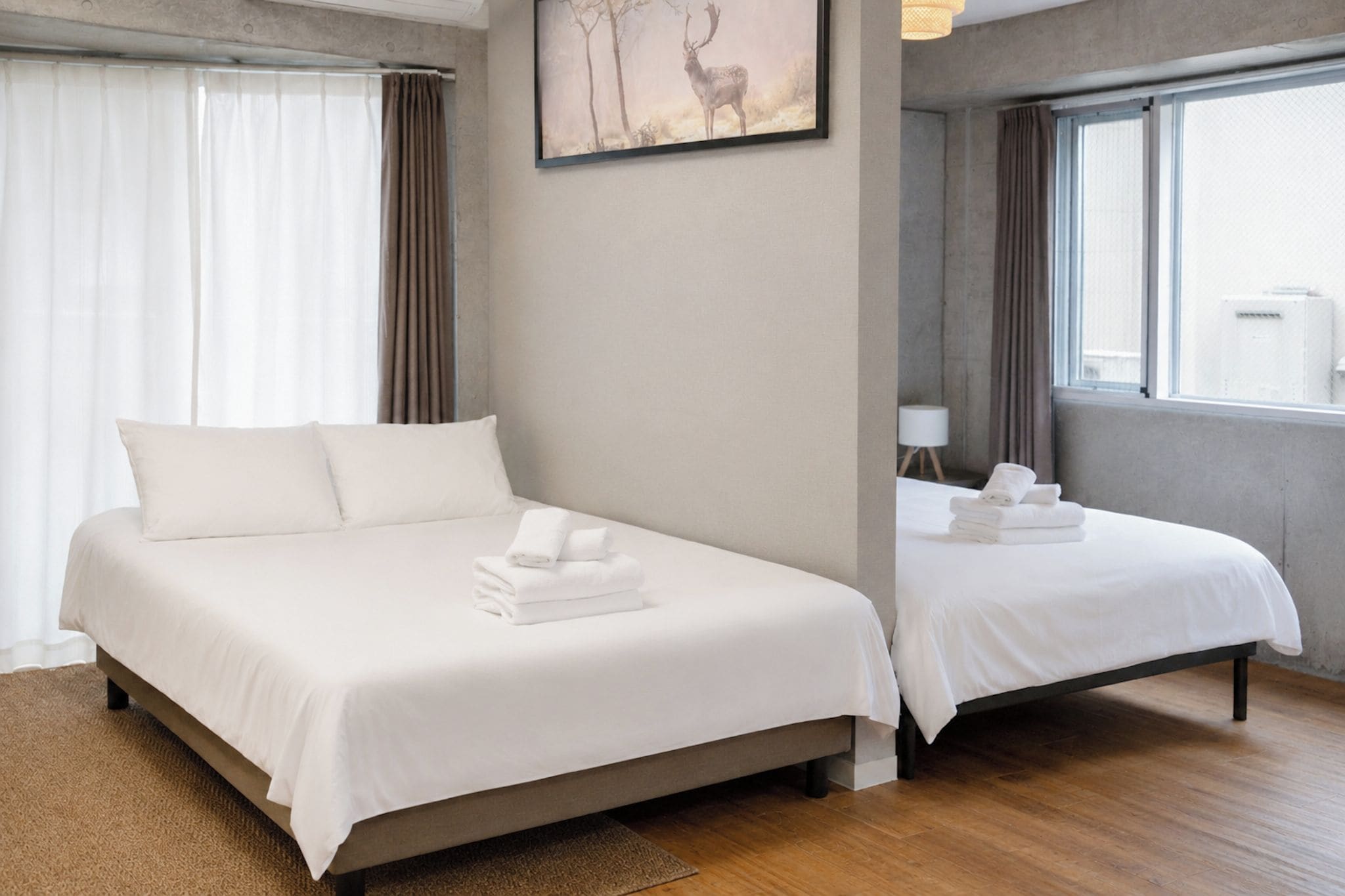 A hotel room with a large bed, a smaller bed, and a painting of a deer on the wall.