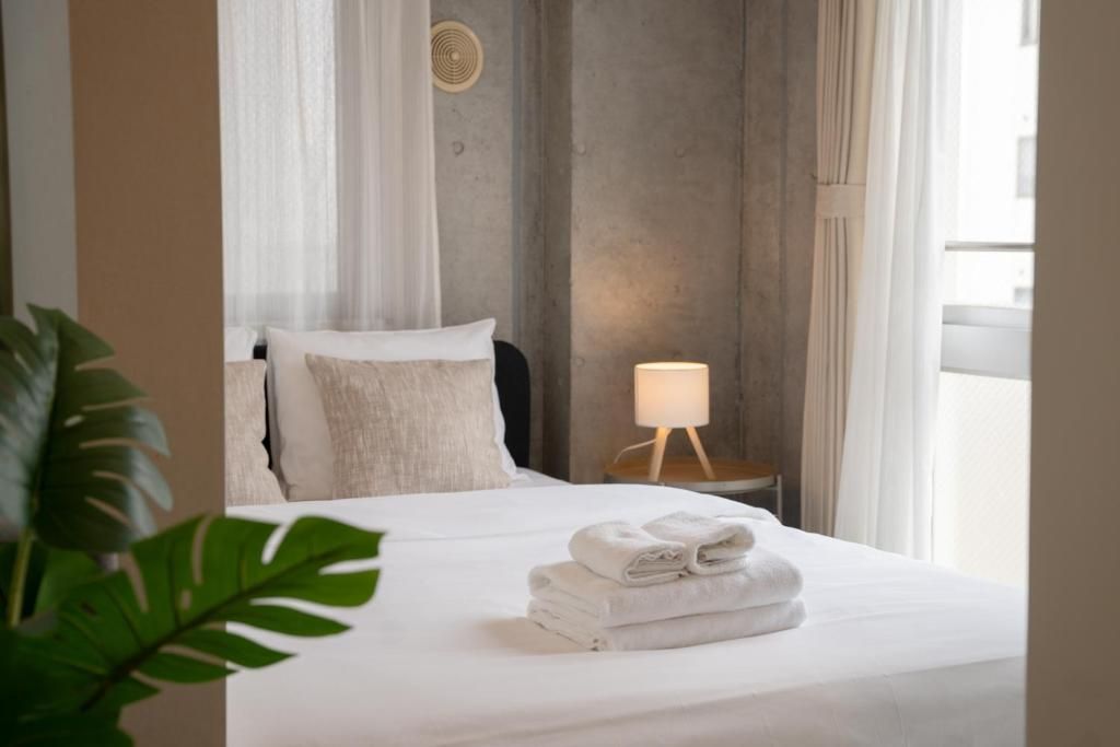 A hotel room with a bed, a bedside lamp, and a view of the outdoors.