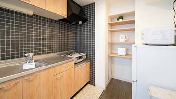 Une cuisine moderne avec des meubles en bois, une cuisinière à gaz, un four à micro-ondes et une petite étagère sur laquelle est posée une plante.